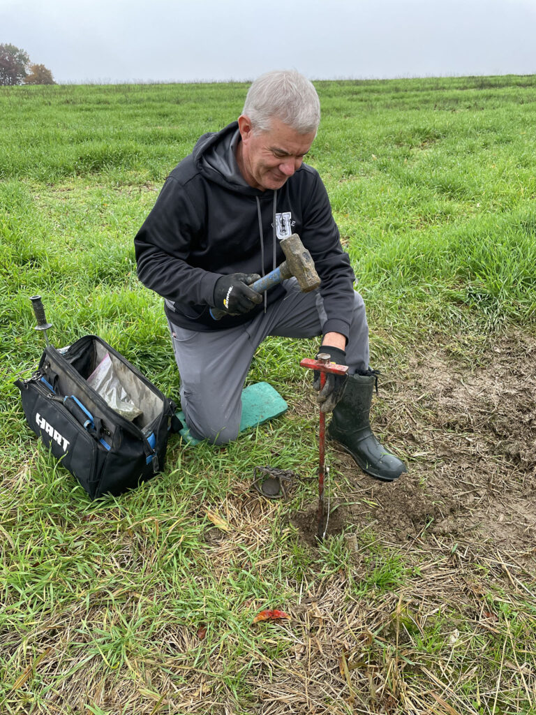 Photo of Dan hammering part of the fox trap into the ground.